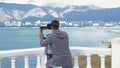 Young man looks through binoculars on observation deck. Media. Man looks through binoculars in rain in summer. View of Royalty Free Stock Photo