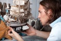 Young man looks at model of sailing ship in vintage interior Royalty Free Stock Photo