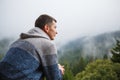 A young man looks out from the hotel`s balcony with a view of the mountains, the fog and the fir forest. Royalty Free Stock Photo