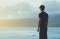 A young man watching the sunset on the beach alone.