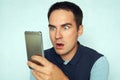 Young man looks at the phone and is surprised by what he saw. Puzzled frightened expression on the face of a guy reading Royalty Free Stock Photo
