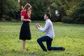 Young man in love proposing to his girlfriend outdoors in the park