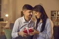 Young man in love tenderly congratulates his girlfriend on Valentine's Day by giving her a gift. Royalty Free Stock Photo