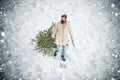 Young man lumberjack is cutting Christmas tree in the wood. Funny Santa man posing with axe and Christmas tree. Man Royalty Free Stock Photo