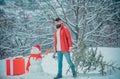 Young man lumberjack is cutting Christmas tree in the wood. Happy father with Christmas tree on a snowy winter walk. A Royalty Free Stock Photo