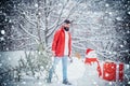 Young man lumberjack is cutting Christmas tree in the wood. Happy father with Christmas tree on a snowy winter walk. A Royalty Free Stock Photo