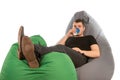 Young man lying on beanbag chairs and drinking coffee