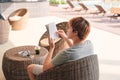 Young man lying on the chaise-lounge and reading a book near the swimming pool Royalty Free Stock Photo