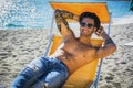 Young man lying on deckchair at beach Royalty Free Stock Photo