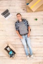 Young man lying on floor surrounded by boxes and laptop smiling cheerful top view Royalty Free Stock Photo