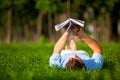 Young man lying on green grass and reading book Royalty Free Stock Photo