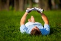 Young man lying on green grass and reading book Royalty Free Stock Photo