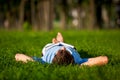 Young man lying on green grass and reading book Royalty Free Stock Photo