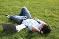 Young man lying on green lawn in park Royalty Free Stock Photo