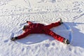 Young man lying in the snow and making a snow angel. Winter walks and fun