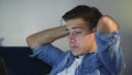 Side view a tired young man is lying on the couch and working on a laptop, typing on the keyboard, remote work from home Royalty Free Stock Photo