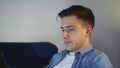 Side view a tired young man is lying on the couch and working on a laptop, typing on the keyboard, remote work from home Royalty Free Stock Photo