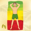 Young man lying on a towel at the beach in the form of a flag of Ethiopia