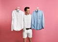 Young man makes a choice of a shirt. Blue or white? what choose? Royalty Free Stock Photo