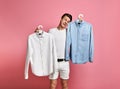 Young man makes a choice of a shirt. Blue or white? what choose? Royalty Free Stock Photo