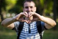 Young man makes hands in shape of love heart