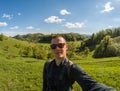 Young man makin selfie on green landscape background