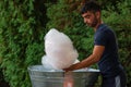 Young man making and selling cotton candy on an alley in the park at a festival in Bucharest, Romania, 2019 Royalty Free Stock Photo