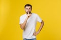 Young man making silence gesture, shhhhh. Isolated over yellow background.