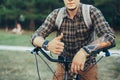 Young Man Is Making Thumb Up By Hands Sitting On A Bicycle On Green Summer Meadow Royalty Free Stock Photo