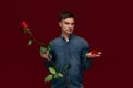 Young man making wedding proposal holding one red rose and box with engagement ring. Royalty Free Stock Photo