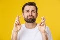 Young man making a wish isolated on yellow background Royalty Free Stock Photo