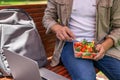 Young man man eating healthy salad outdoors from transparent container