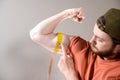 Young man measuring biceps, muscles of his arm with a yellow tape measure Royalty Free Stock Photo