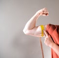 Young man measuring biceps, muscles of his arm with a yellow tape measure Royalty Free Stock Photo