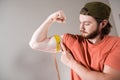 Young man measuring biceps, muscles of his arm with a yellow tape measure Royalty Free Stock Photo