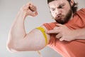 Young man measuring biceps, muscles of his arm with a yellow tape measure Royalty Free Stock Photo