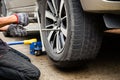 Young man mechanic wearing gloves,car repair,changing tire using wrench to fix car wheel flat tire on the road,transportation and Royalty Free Stock Photo