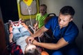 Young man in a medical uniform holding an oxygen mask on a woman`s face lying on a stretcher, little sad girl sitting