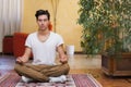 Young man meditating on his living room floor
