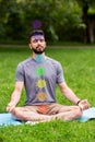 young man meditating at park with seven chakras Royalty Free Stock Photo