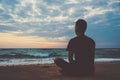 Young man meditating on top ocean cliff during sunset. Royalty Free Stock Photo