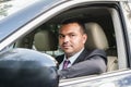 Young man of Middle Eastern appearance in a business suit is driving an expensive car
