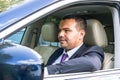 Young man of Middle Eastern appearance in a business suit is driving an expensive car