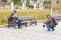 A young man in a military uniform of the Red Army Commissioner during the civil war period sits on a bench and plays the harmonic