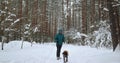 A young man, releases a dog from a leash during a winter walk in a forest