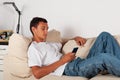 young man with mobile phone lying on sofa at home Royalty Free Stock Photo
