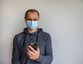 Young man with mobilphone wearing a protective medicine mask isolated on white background Royalty Free Stock Photo