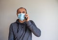 Young man with mobilphone wearing a protective medicine mask isolated on white background. COVID-19 pandemic concept. Copy space Royalty Free Stock Photo