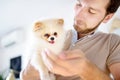 Young man with 2-month old pomeranian spitz puppy. Loving male owner with his domestic pet