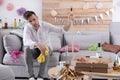 Young man with mop suffering from hangover in room after party